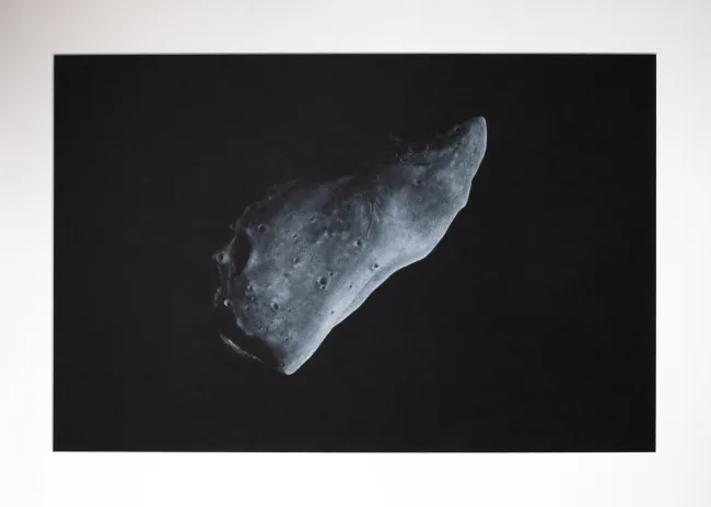 black and white asteroid named Gaspra, with little light from above on black background