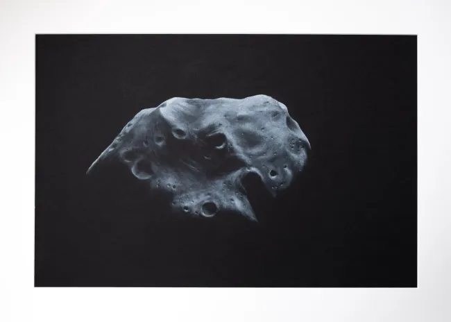 black and white asteroid named Lutetia, with little light from above on black background